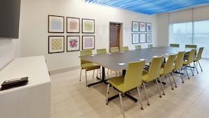 A conference room with a long table, yellow chairs, framed artwork on the walls, and a ceiling with blue lighting. - Holiday Inn Express & Suites Plano East - Richardson by IHG (Plano)