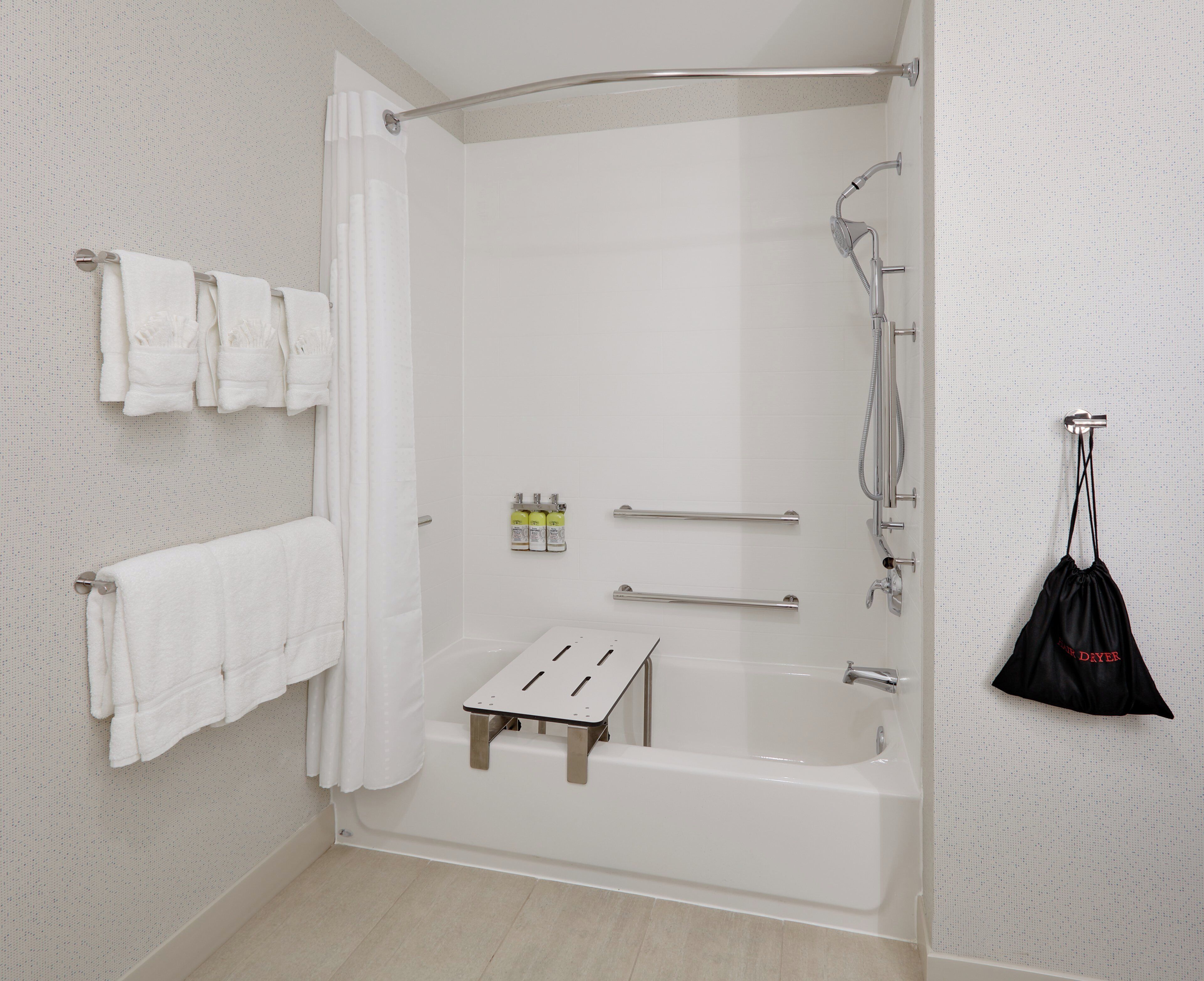 Une salle de bain moderne équipée d’une baignoire, d’une douche et de barres d’appui.