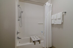 Un bagno con doccia, vasca da bagno, un piccolo sgabello e un appendi asciugamani.