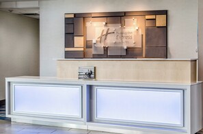 A reception desk with a modern design, featuring a welcome sign and a framed photo above it.