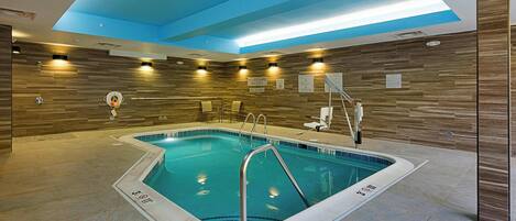 Una piscina interior con techo azul, paneles de pared de madera y un letrero de salvavidas.