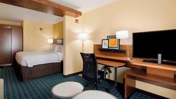 Een hotelkamer met een bed, bureau, stoel, televisie en twee kleine tafels.