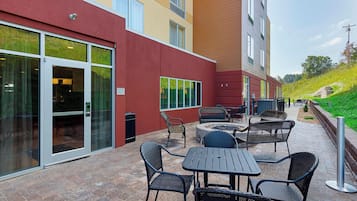 An outdoor patio with a fire pit, seating, and a glass door entrance.