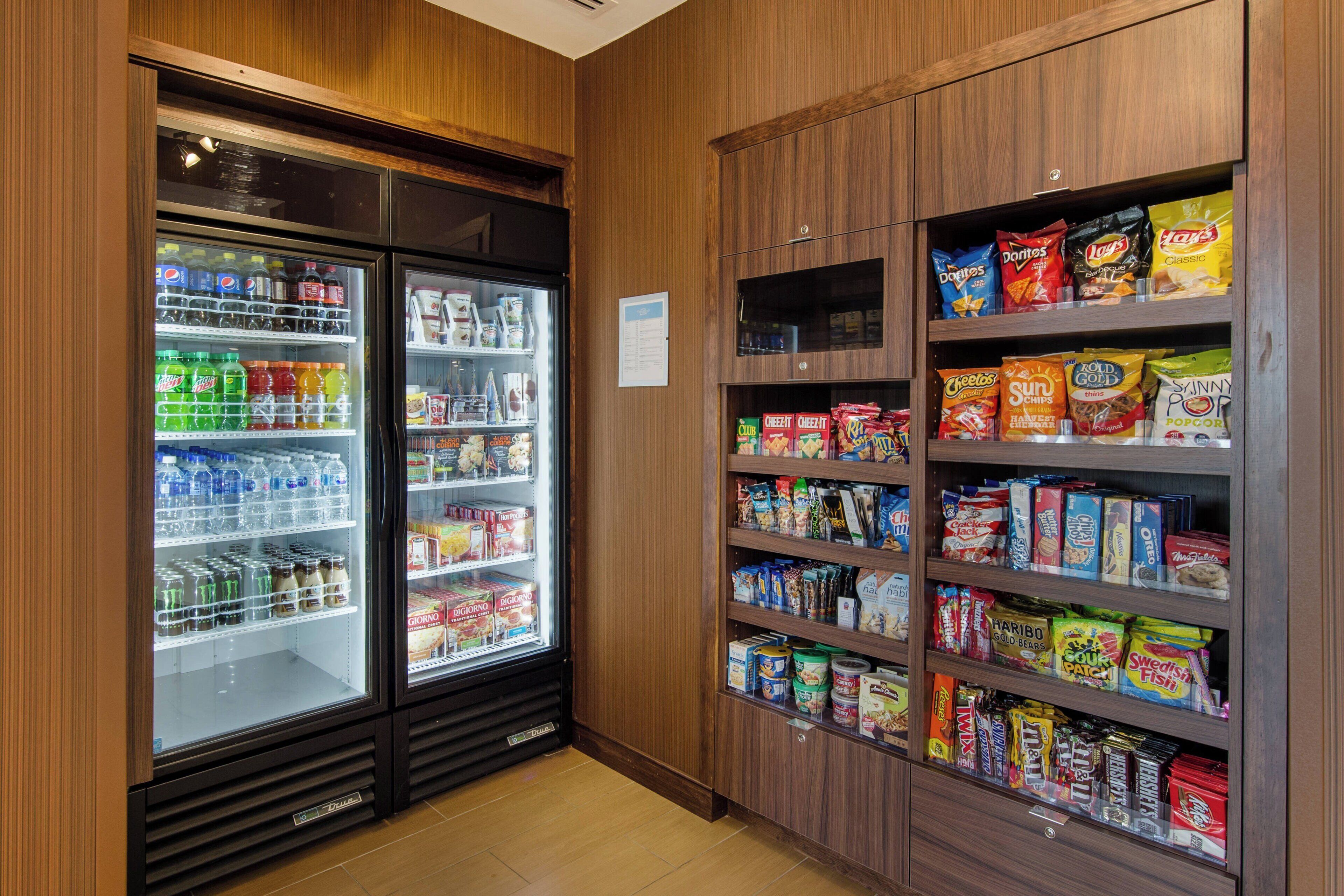A snack and beverage refrigerator with shelves stocked with various snacks and drinks.
