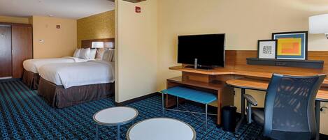 A hotel room with a bed, a desk, a chair, a TV, and two small tables.