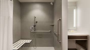Un baño moderno con cabina de ducha, barras de apoyo y un asiento.