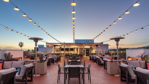An outdoor patio with tables and chairs, string lights, and a bar area. - Hilton Garden Inn Santa Barbara / Goleta (Goleta)