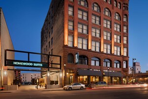 Un hotel con una entrada destacada que indica “Homewood Suites”, con una fachada clásica de ladrillo y varias ventanas.
