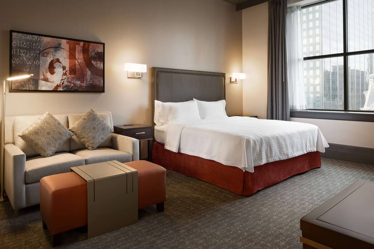 Ein Hotelzimmer mit einem Bett, einem Schlafsofa, einem Nachttisch und einem Bild an der Wand.