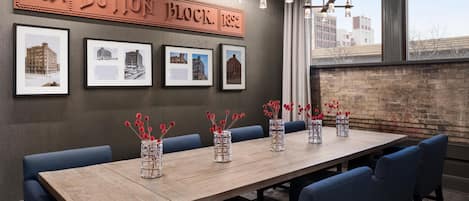 A conference room with a long table, blue upholstered chairs, and framed architectural photos on the wall.