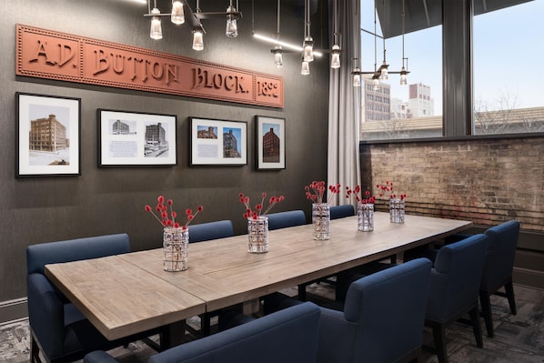 A conference room with a long table, blue upholstered chairs, and framed architectural photos on the wall.