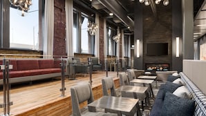 Ein modernes Restaurant mit Holzboden, grau gepolsterten Sitzgelegenheiten und einem Kamin.