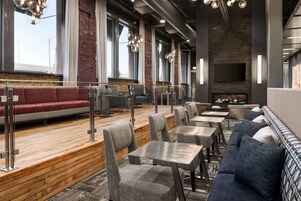 Un restaurante moderno con suelo de madera, asientos tapizados en gris y una chimenea.