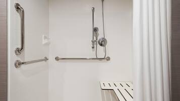 Un espace douche équipé d’une barre d’appui, d’un pommeau de douche à main et d’un flexible de douche.