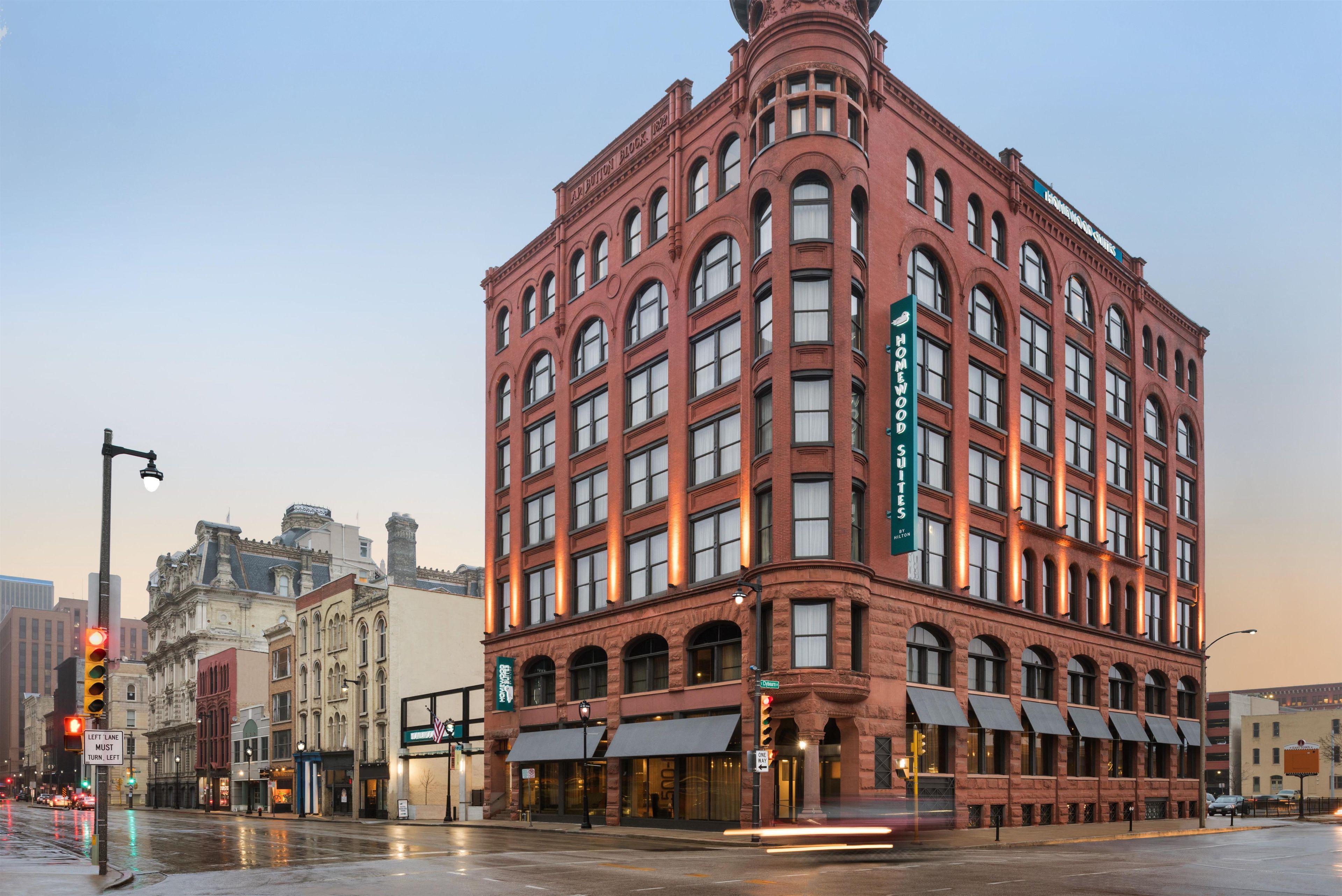 A red brick building with multiple windows and a sign for 'Homewood Suites by Hilton.'