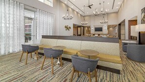A modern hotel lobby with a seating area, a bar, and a television screen. - Homewood Suites By Hilton Schenectady (Schenectady)