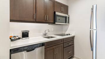 A modern kitchen with stainless steel appliances, a dishwasher, and brown cabinetry.