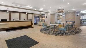 A hotel lobby with a reception desk, seating area, and a fireplace. - Homewood Suites By Hilton Schenectady (Schenectady)