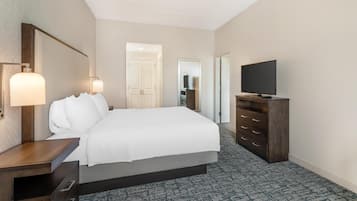 Una habitación de hotel con cama, mesita de noche, televisor y cómoda.