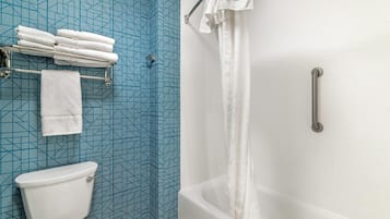 Un bagno con il water, una doccia con maniglione e un portasciugamani con asciugamani piegati.