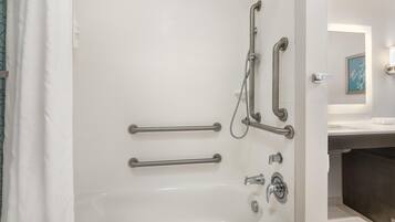 Un baño moderno con bañera, barras de apoyo y cabezal de ducha.