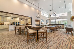A spacious dining area with multiple tables and chairs, a kitchen in the background, and large windows allowing natural light. - Homewood Suites By Hilton Schenectady (Schenectady)
