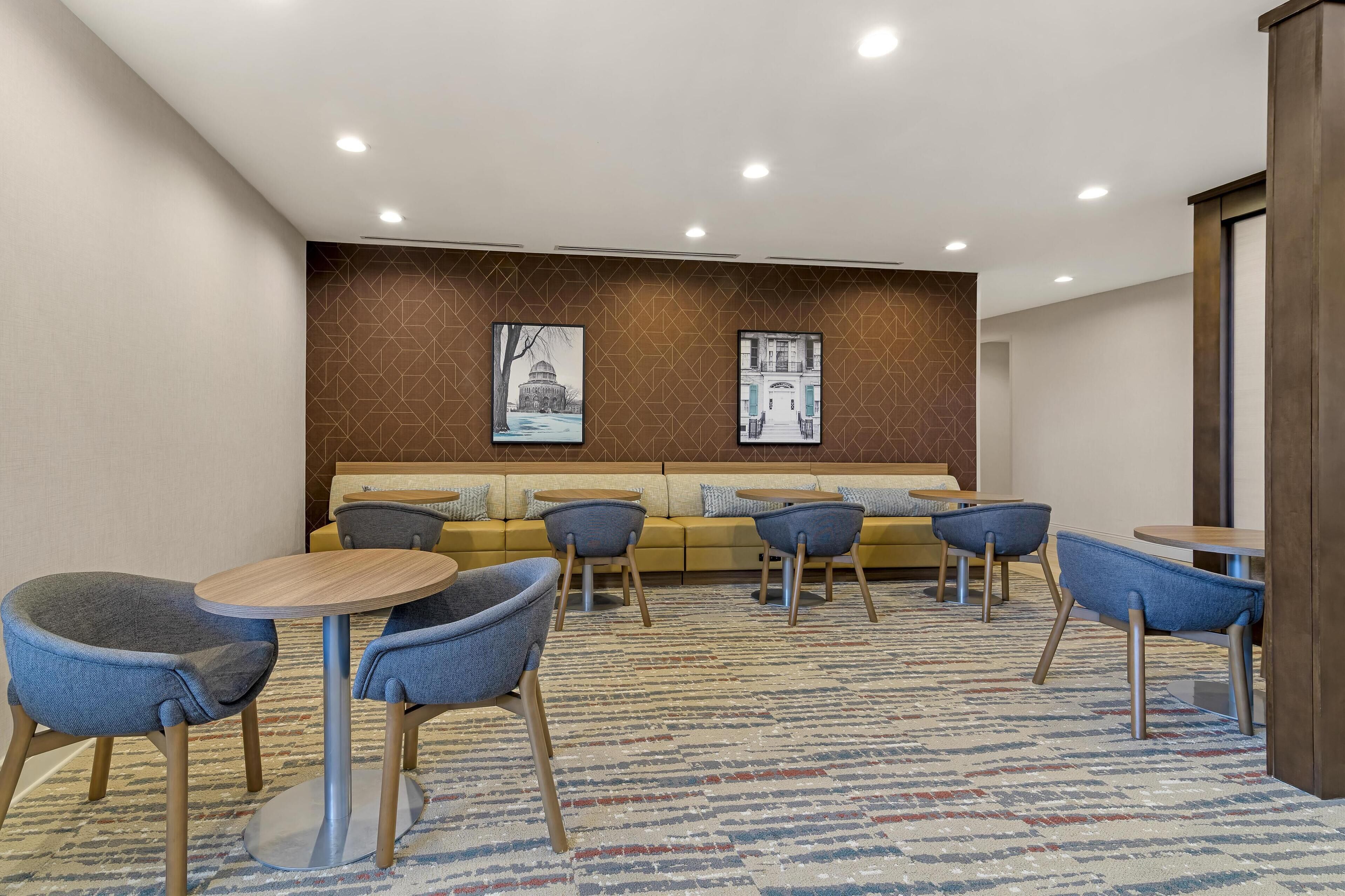 Un hall de hotel con un sofá, sillas y mesas.