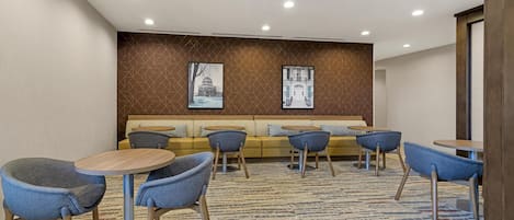 Un hall de hotel con un sofá, sillas y mesas.