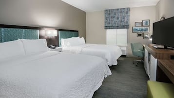Habitación de hotel con dos camas, un escritorio con ordenador, televisor y ventana con vistas.