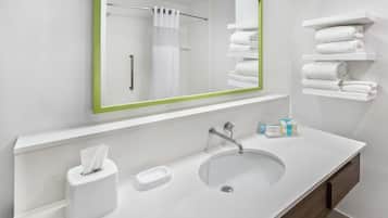 Un baño moderno con un lavamanos blanco, un espejo con marco verde, un perchero y una repisa con toallas dobladas.