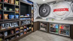 Un espace dédié aux collations et aux boissons, avec des étagères remplies de chips, de bonbons et de boissons réfrigérées.