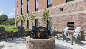 A fire pit with chairs around it, set against a brick building. - Hampton Inn Westfield (Westfield)