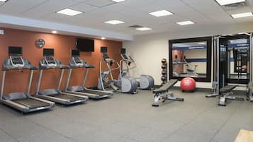 A gym with treadmills, elliptical machines, a stationary bike, and a weightlifting area.