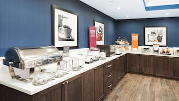 A breakfast bar with a self-service coffee station, a buffet area, and framed pictures on the wall.