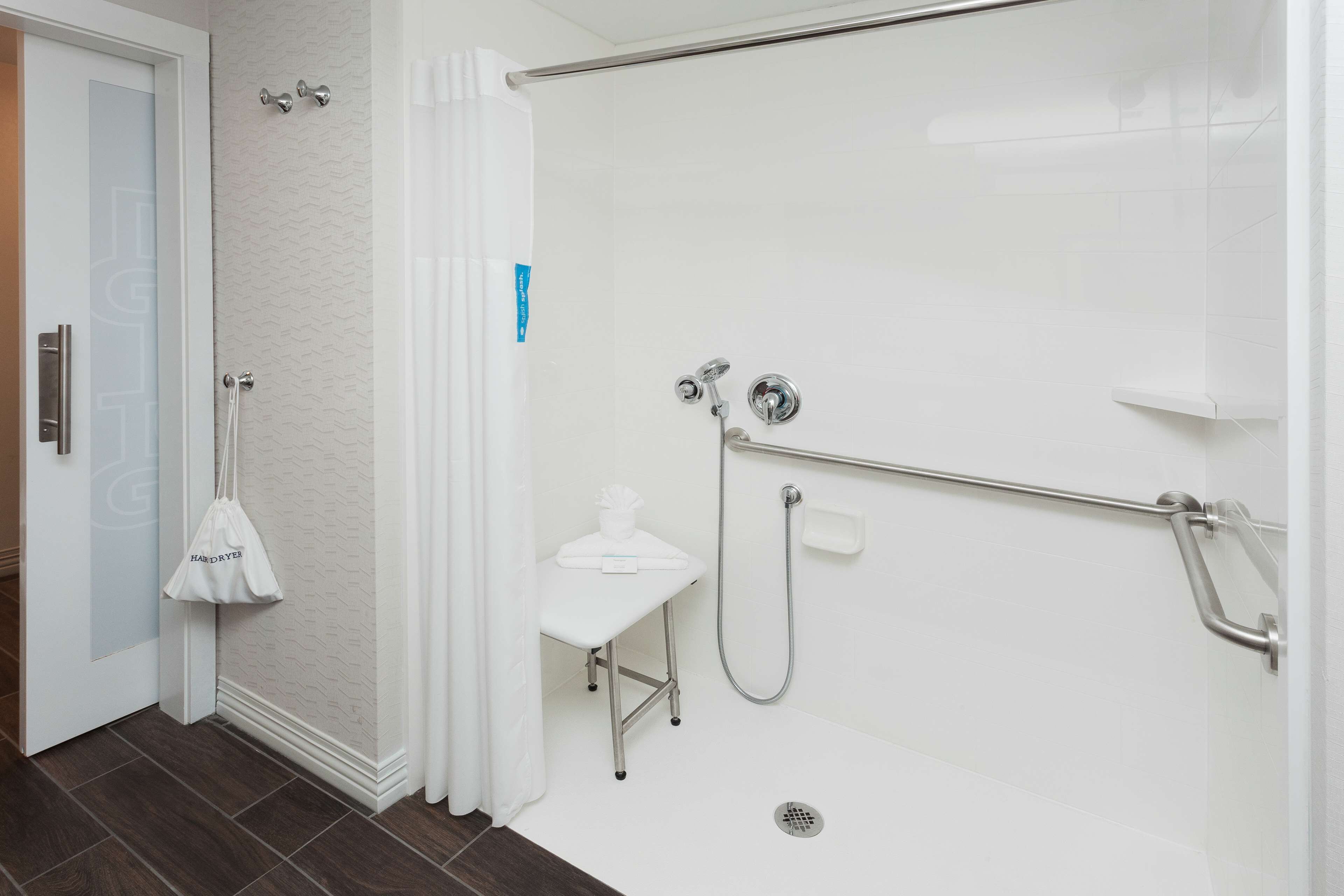 Un baño moderno con ducha, inodoro y una mesita con una toalla.