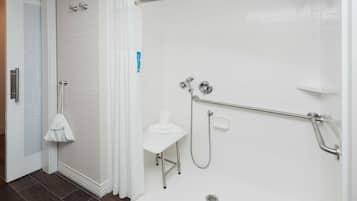 Un baño moderno con ducha, inodoro y una mesita con una toalla.
