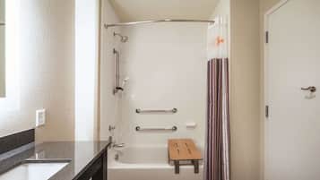 A bathroom with a bathtub, a shower, a vanity with a sink, and a shower curtain.