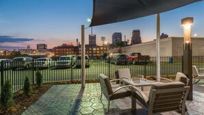 An outdoor patio with seating and a view of a cityscape at dusk. - La Quinta Inn & Suites by Wyndham Memphis Downtown (Memphis)