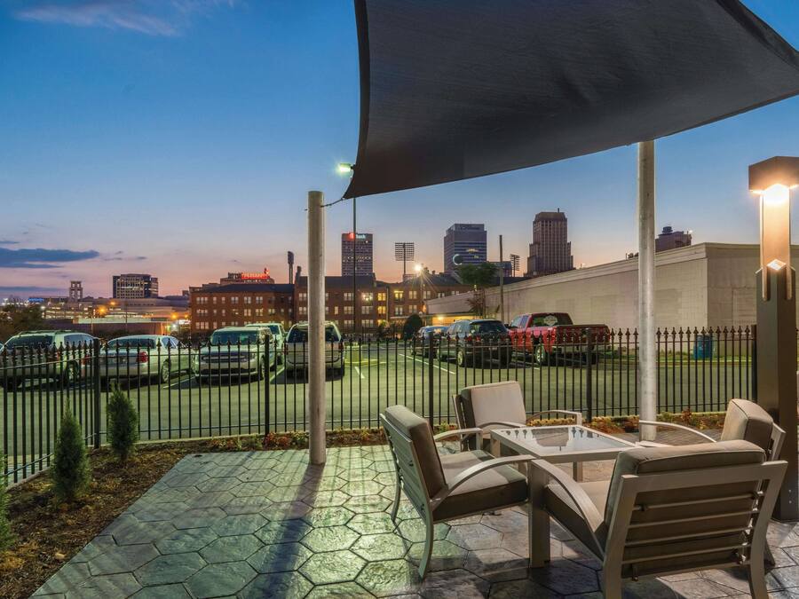 An outdoor patio with seating and a view of a cityscape at dusk.