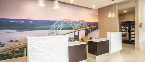 A reception area with a mural of a bridge, a reception desk, and a refrigerator.