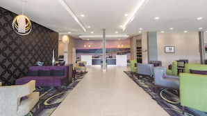 A lobby with a reception desk, seating area, and a mural of a sunset over a bridge. - La Quinta Inn & Suites by Wyndham Memphis Downtown (Memphis)