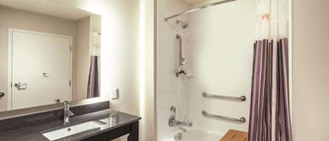 A bathroom with a sink, mirror, shower, and a wooden stool.