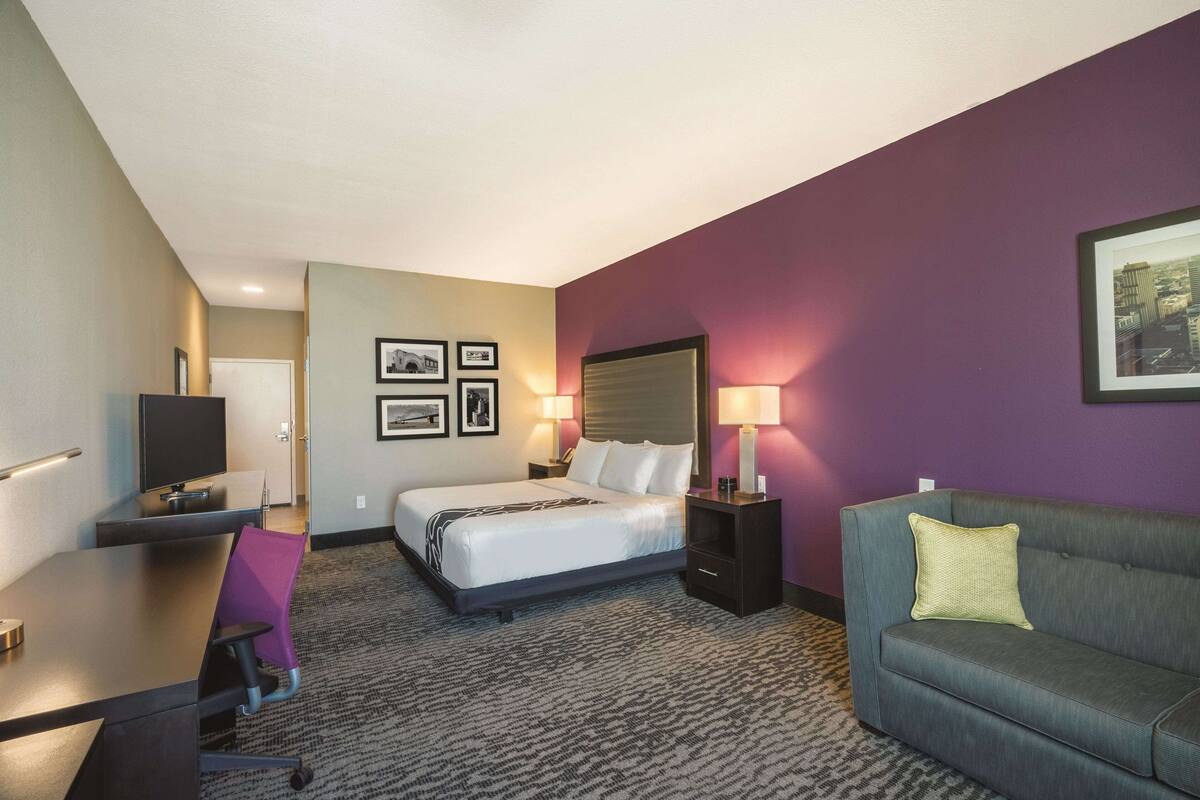 A hotel room with a bed, a desk, a couch, and a TV.
