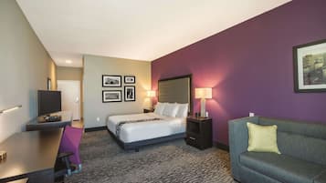 A hotel room with a bed, a desk, a couch, and a TV.