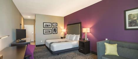 A hotel room with a bed, a desk, a couch, and a TV.