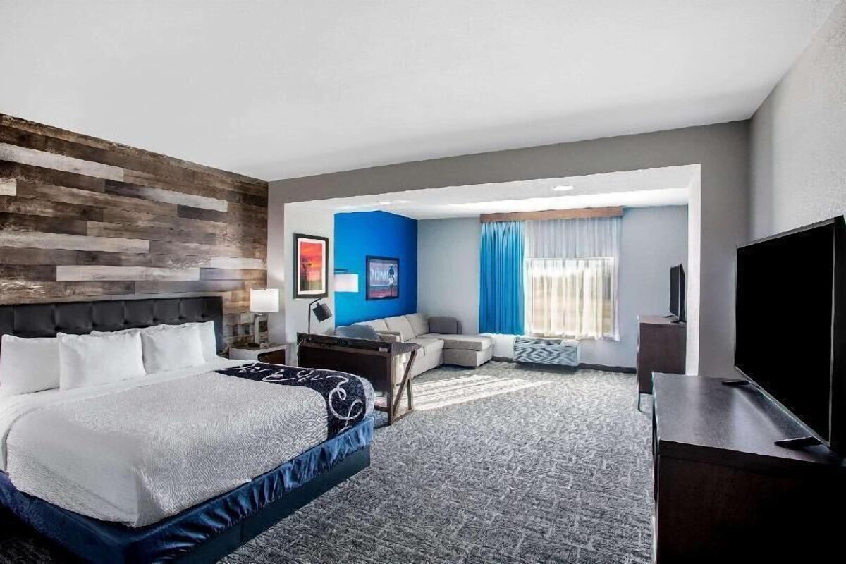 A hotel room with a bed, a sofa, a TV, and a desk.