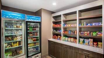 Un angolo dedicato a snack e bevande self-service, con banchi frigo e scaffali pieni di diversi prodotti.