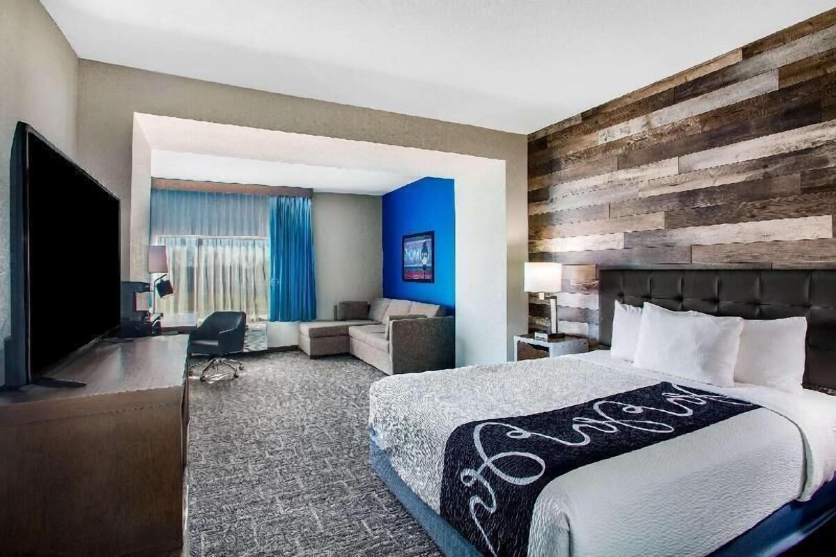 A hotel room with a large bed, a television, a desk, and a seating area with a sofa and armchairs.