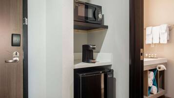 A compact kitchenette with a microwave, coffee maker, and refrigerator.