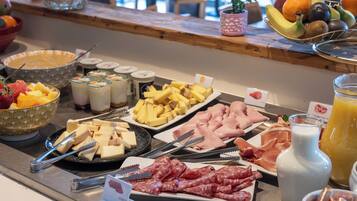 En buffé med ett varierat utbud av mat, inklusive frukt, ostar, kött och drycker.
